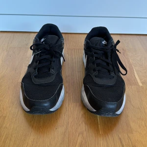 Svarta Nike Air sneakers - Säljer ett par svarta Nike Air sneakers i bra skick. De har en klassisk design med vit sula och vit Nike-logga på sidan. Skorna har snörning och är perfekta för vardagsbruk. De är bekväma och stilrena, passar till det mesta!