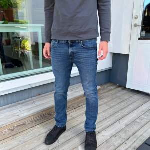 Säljer ett par snygga blå jeans från Dressmann. De har en klassisk straight fit och är perfekta för både vardag och fest. Jeansen är i bra skick och har en bekväm passform med normal midja. Perfekta för höst och vår!