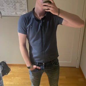 J.Lindeberg Pikétröja - Riktigt schysst och unik J.Lindeberg pikétröja med en söm som går ner från kragen. Perfekt för dig som vågar stå ut lite. Riktigt schysst blandning av en piké och skjorta. Size S. Priset är ej hugget i sten! Hör gärna av dig vid frågor😊