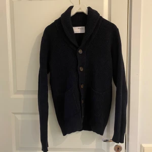 Cardigan - Säljer en stickad mörkblå cardigan / kofta från selected homme storlek M i mycket fint skick. Liten i storlek så efterliknar storlek S. Passar perfekt för mig som är 180 lång.  Mått: Total längd - 65cm Bröstvidd - 52cm Axelbredd - 45cm Arm - 54cm