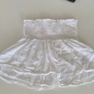 Vit kjol från Gina Tricot - Säljer en superfin vit blus från Gina Tricot i storlek 158/164. Blusen har en ribbad del som ger en bekväm och flexibel passform. Den är gjord i ett lätt och luftigt material, perfekt för varma sommardagar. Den kan även andvändas som en kjol. 