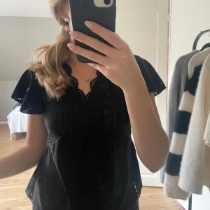 Svart blus med spetsdetaljer - Perfekt för både vardag och fest. Blusen har en fin passform och är i nyskick.