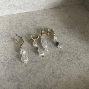 Guldörhängen med vita pärlor och blå detalj - Säljer ett par eleganta guldörhängen med vita pärlor. Ena örhänget har en unik blå pärldetalj som ger en fin kontrast. Perfekta för både vardag och fest! ✨