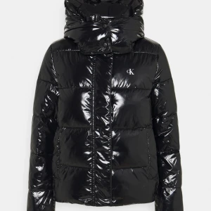 CALVIN KLEIN JACKA - En skön och gosig jacka, som håller dig varm under hela vintern! Den är helt glansig, enfärgat och har en logga vid högra bröstet. Passformen är  slim fit. Säljer pågrund av att den inte kommer till någon användning. Den är även helt slutsåld!