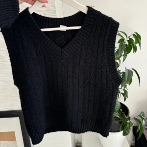 Svart stickad väst - Säljer en snygg svart stickad väst med v-ringning. Perfekt för lager-på-lager under höst och vinter. Västen har en ribbad kant vid ärmhålen och nederkanten, vilket ger en stilren look. Storlek s men passar xs också!
