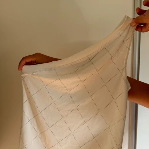 One shoulder topp - Toppen är i mycket bra skick. Bara använd några få gånger. Toppen är vit med silvrigt mönster. Den är one shoulder. Storlek xs