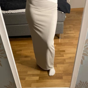 Beige ribbad långkjol - Säljer en stilren beige långkjol med ribbad struktur. Kjolen har en tight passform som framhäver figuren och är perfekt för flera olika outfits. Köpt på hm ocj använd ca 5 gånger🩷