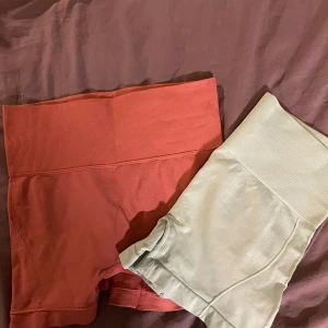 Två par cyckelbyxor i olika färger - Säljer två par cyckelbyxor i olika färger. Ett par är i en mjuk persikofärg och det andra i en ljus mintgrön nyans. Båda har en ribbad hög midja och är perfekta för träning eller avslappning. Materialet är stretchigt 