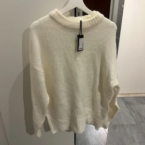 Vit stickad tröja från 157 - Säljer en vit stickad tröja från 157. Tröjan har en ribbad krage, ärmslut och nederkant. Aldrig använd.