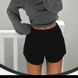 Svarta shorts med hög midja - Snygga svarta shorts med hög midja och knappdetalj framtill. Perfekta för en stilren look, dessa shorts har en klassisk passform som passar till många olika outfits. aldrig använd, sälja för att det är för stor för mig!
