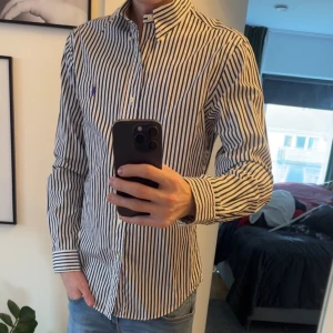 Randig skjorta från Ralph Lauren - Snygg och stilren skjorta från Ralph Lauren med svartvita ränder. Säljer den för den aldrig kommer till användning. Den är i nyskick använd 2 gånger. Storlek M