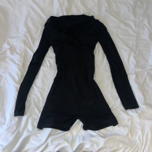 Svart långärmad bodysuit  - Snygg svart jumpsuit med långa ärmar och en figurnära passform. Perfekt för en stilren look. Materialet är mjukt och stretchigt för extra komfort.