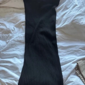 Svart ribbad klänning från Lindex - Snygg svart ribbad kjol från Lindex i storlek XS. Perfekt för en stilren look med sin tighta passform och enkla design. Kjolen är 3/4 vilket innebär att den inte går hela vägen ner till marken. Säljer då den inte kommit till användning av mig utan bara min mamma. Lite nopprig på några ställen men de går att fixa med noppermaskin!