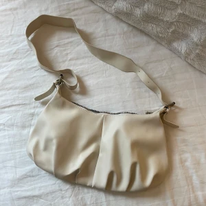 Beige axelväska med dragkedja - Snygg beige axelväska med justerbar rem och dragkedja. 34cm lång, 18cm hög