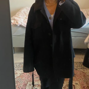 Gina kappa - Säljer en  svart kappa med knyt i midjan från Gina , storlek S men passar till M hade jag sagt. Den har långa ärmar och knappar framtill.