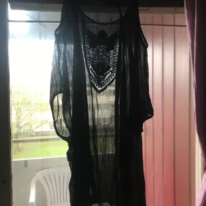 Svart transparent klänning från Monrow - Säljer en svart transparent klänning från Monrow i storlek S. Klänningen har ett snyggt broderat mönster framtill och är ärmlös. Perfekt för lager-på-lager-stil eller som strandklänning. 🖤