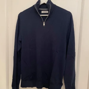 Half Zip Jack&Jones Tröja  - Säljer en stilren mörkblå tröja från Jack & Jones. Tröjan har en praktisk dragkedja vid halsen och långa ärmar. Perfekt för en avslappnad look. Skick 10/10