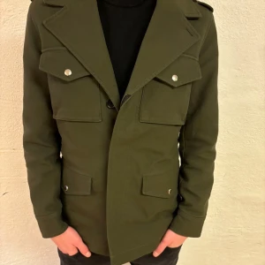 Olivgrön jacka från Zadig & Voltaire - Snygg olivgrön jacka från Zadig & Voltaire med klassisk design. Jackan har långa ärmar och flera fickor med knappar framtill. Perfekt till våran som börjar närma sig. Helt ny tags finns kvar