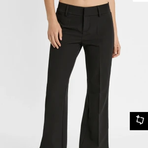 Svarta kostymbyxor med bootcut - Snygga svarta kostymbyxor med bootcut-stil. Byxorna har en klassisk design med dragkedja och knappar framtill.