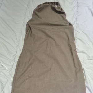  klänning från NA-KD - Snygg beige klänning från NA-KD i en stilren design. Klänningen har en elastisk detalj upptill och är perfekt för en chic look. Den är tillverkad i ett mjukt material som ger en bekväm passform.