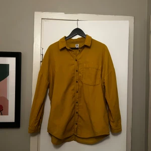 Senapsgul skjorta från BDG - Säljer en snygg senapsgul skjorta i manchestertyg från BDG i storlek M. Skjortan är tillverkad i 100% bomull och har långa ärmar samt en klassisk krage. Perfekt för en stilren look. 🟡