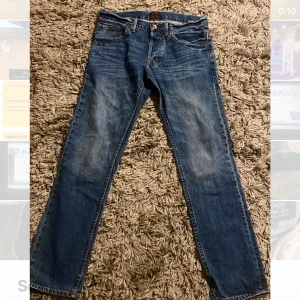 Blå jeansbyxor - Snygga blå jeansbyxor med klassisk femficksdesign och knappgylf. Midjemått är 31 och längd 32.