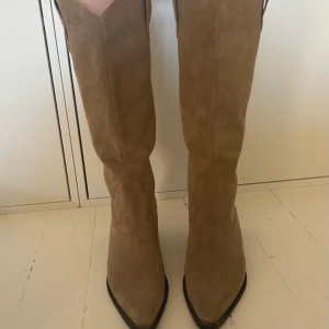 Beige cowboy boots - Snygga beige cowboy boots i mocka med spetsig tå och låg klack. Använda ungefär 3 gånger.