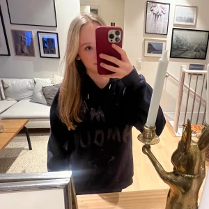 Svart hoodie med text - Säljer en svart hoodie med glittrig text på framsidan. Den har en klassisk design med huva och dragsko. Perfekt för en avslappnad stil.