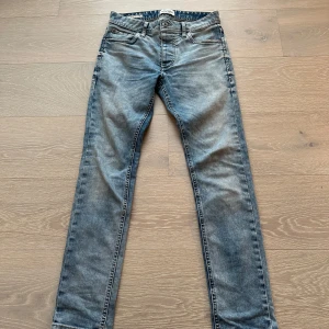 Ljusblå jeansbyxor - Snygga blå jeansbyxor från Jack and Jones med en klassisk femficksdesign. De har en lätt tvättad look och en knappgylf. Jeansen har passformen slim fit och sitter väldigt bra på benen. Storleken är 27/30