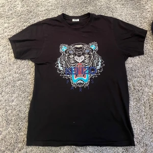Kenzo t-shirt - Snygg svart t-shirt från Kenzo med ett coolt tigertryck i blått och rött på framsidan. Perfekt skick
