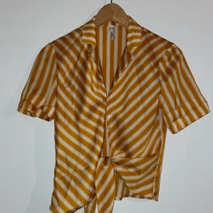 Satinskjorta från Mango - Säljer denna satinskjorta från Mango, i en fin gul-orange färg. Den är i storlek xs och jag säljer den då den är för liten på mig. Man knyter den i midjan. Använd Max 3-4 ggr så den är i väldigt fint skick🥰✨ Nypris var 300kr. 
