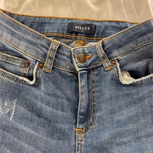 Blåa Jeans  - Tighta jenas i stretch material. Använda ett fåtal gånger men hann tyvärr växa ur dem ganska snabbt. Jeansen har små detaljer längs benen (bild 3).  