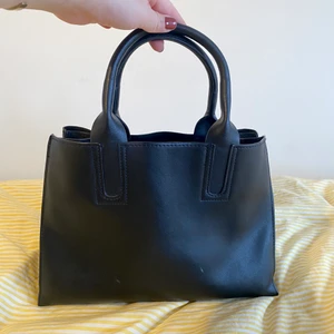 Handväska - Fin handväska från Åhléns!! Perfekt att slänga på axeln alt fästa axelrem i (medföljer ej) Den är i jättefint skick förutom två små repor fram på väskan som syns på första bilden. Lite osäker på material med den känns/ser ut som läder!🥰❤️