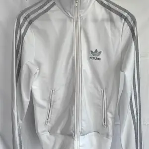 Adidas tröja med dragkedja storlek EU34. Vit med silverdetaljer/ märke. Snygg, skön och bra passform. Kan skickas spårbart 66kr!
