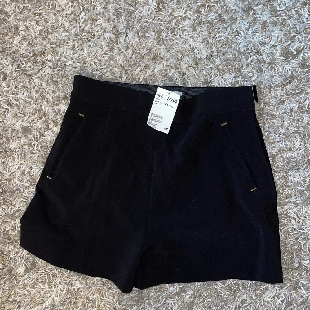 Oanvända svarta shorts med gulddetaljer från H&M, lappen kvar. . Shorts.