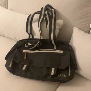  tygväska  - köpt Second hand Så vet inte märke men står ZACK i fram på den. har använt den någon enstaka gång. fint skick! svart fast typ marinblå ibland jag vet inte lol med vita detaljer