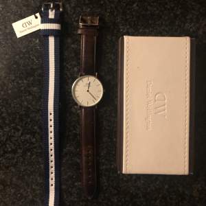 Jag säljer min Daniel Wellington klocka som är silver färgad samt har en vit urtavla. Det tillkommer även ett brunt läderband samt ett oanvänt blå/vitt band. Klockan är i ett bra och välmående skick. Skriv gärna vid fler funderingar.