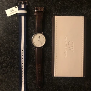 Daniel Wellington Klocka - Jag säljer min Daniel Wellington klocka som är silver färgad samt har en vit urtavla. Det tillkommer även ett brunt läderband samt ett oanvänt blå/vitt band. Klockan är i ett bra och välmående skick. Skriv gärna vid fler funderingar.