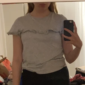 Grå t-shirt med volang - Grå t-shirt med volang, köpt från bik-bok i strl M.   Vid frågor är det bara att skriva!🥰  Nytvättad!