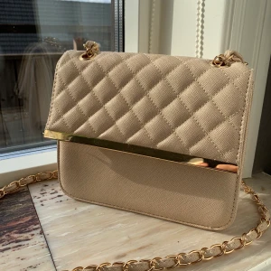 Väskor  - Jag säljer denna superfina väska som jag knappt använt. Den har en superfin beige färg med guld detaljer. 