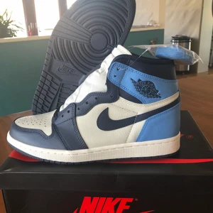 Jordan 1 high obsidian - Helt nya Jordan 1 high obsidian. Dom är i storlek 42,5 och är som sagt i helt perfekt skick. Boxen är även den i mycket bra skick. Med skon ingår även ett extra par ljusblåa snören. Budgivning pågår och för frågor, skriv i DM👍🏼