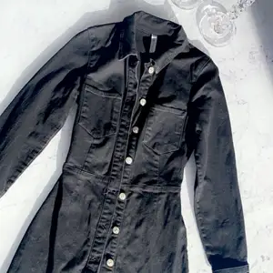 En svart jeans klänning med knappar den är tajt specielt vid midjan, ger dig en form jätte fin!!