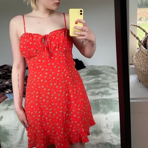 Röd klänning - Otroligt gullig röd, sommarklänning från Urban Outfitters! Blommig o med volang längst ner, snörning vid bröstet. Den är lite insydd vid bröstet pga för vid för mig där, men det är bara att sprätta upp sömmen o den är original igen. Är lite rödare irl!