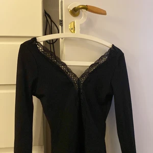 Body med spets - Jättefin body med en spets remsa ner till naveln ca. Den är långärmad och ribbad. Den gör så att man får en snygg clevage  under spetstyget. Säljer pga för liten, använd bara en gång.