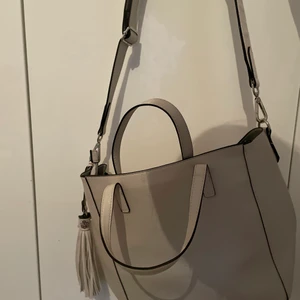Beige väska  - Helt oanvänd beige väska. Man kan ha den på flera olika sätt som man kan se på bilderna. För fler detaljerade bilder kom privat. 