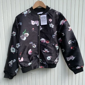 Bomberjacka med blommor NY - Sprillans ny bomberjacka som aldrig kommit till användning. Svart med blommor. Från Monroe World Perfekt nu under hösten! 