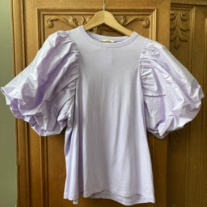 Hm top med puffärm, stl M - Ljuslila fantastisk och populär top med puffärm, 100 % bomull. Stl M. Aldrig använd, prislapp kvar.