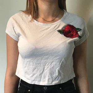 Vit croppad t-shirt🤍 - Vit t-shirt från H&M med ros på. I princip aldrig använd. Storlek S men passar liten M. Kan fraktas, frakt ligger på 70kr. Skriv för mer info🥰🤍