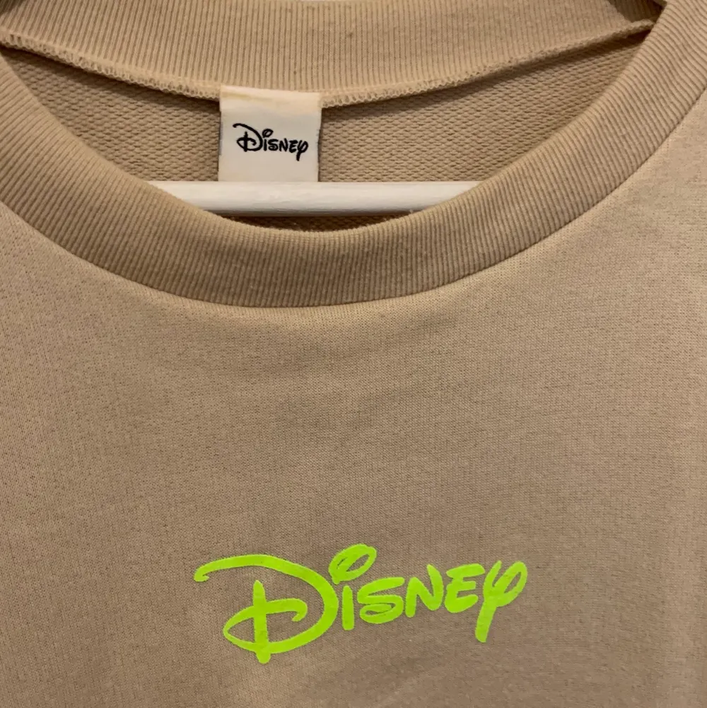 Beige sweatshirt med neon-text. Obs inte från officiella Disney-märket utan är bara ett tryck. Står ingen storlek så jag har uppskattat den till S/M. Frakt 20kr eller gratis vid köp av fler än ett plagg💕. Tröjor & Koftor.