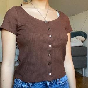 Brun tshirt - Superskön trendig tshirt i jättefin brun färg! Knapparna går att knäppa upp om man vill. Storlek S men tycker den sitter liiite löst på mig. Sparsamt använd